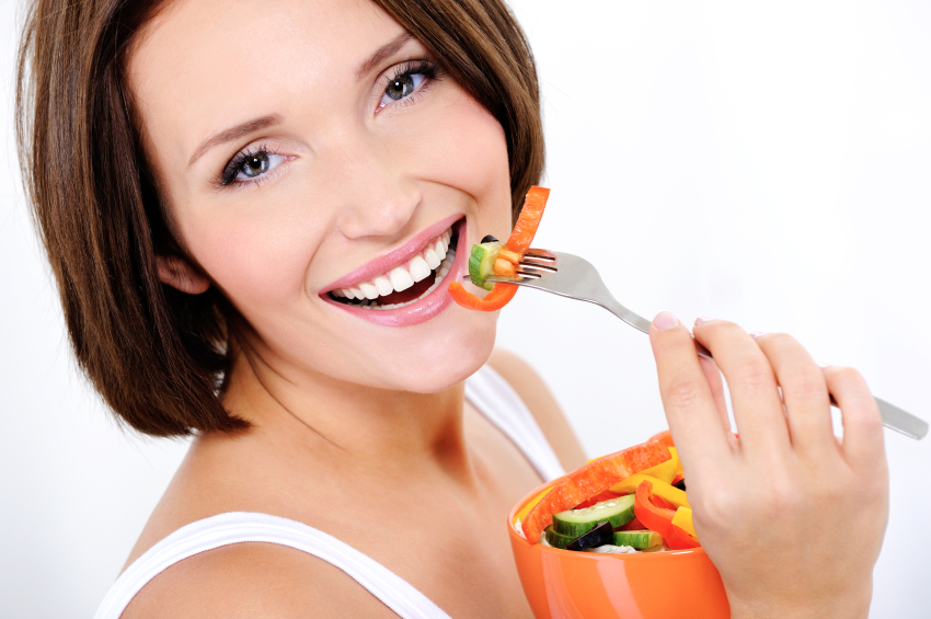 Portrait of a happy attractive young woman eats vegetable salad